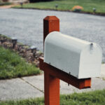 An image of a white mailbox with a red post.